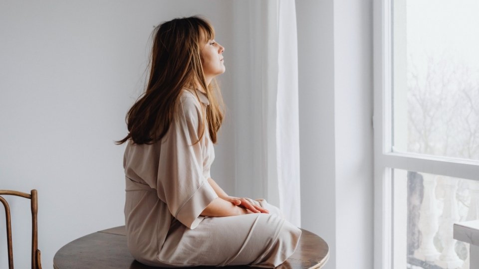 Are Muscle Relaxers Addictive a woman sits on a table while looking out the window.